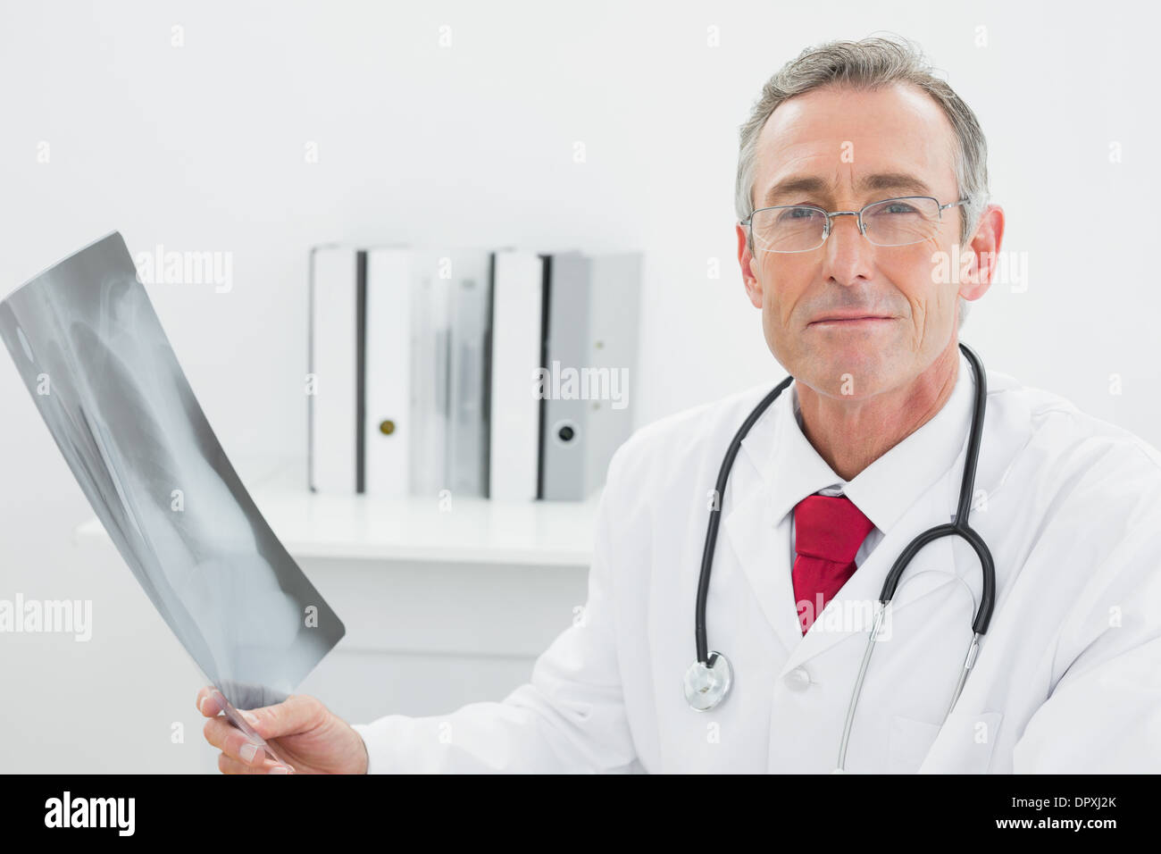 Confident doctor with x-ray picture of lungs in office Stock Photo