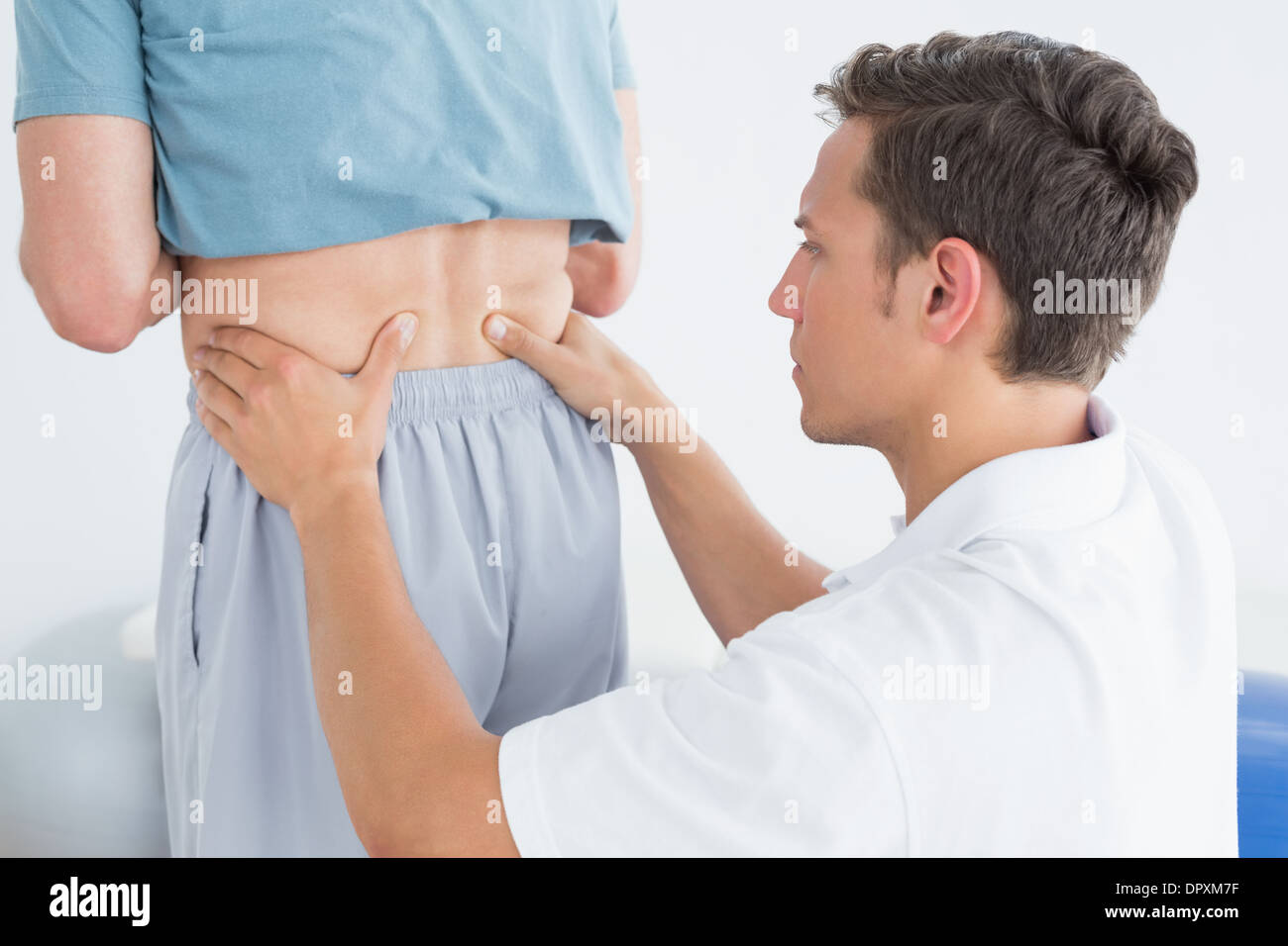 Hands massaging mans lower back in gym hospital Stock Photo