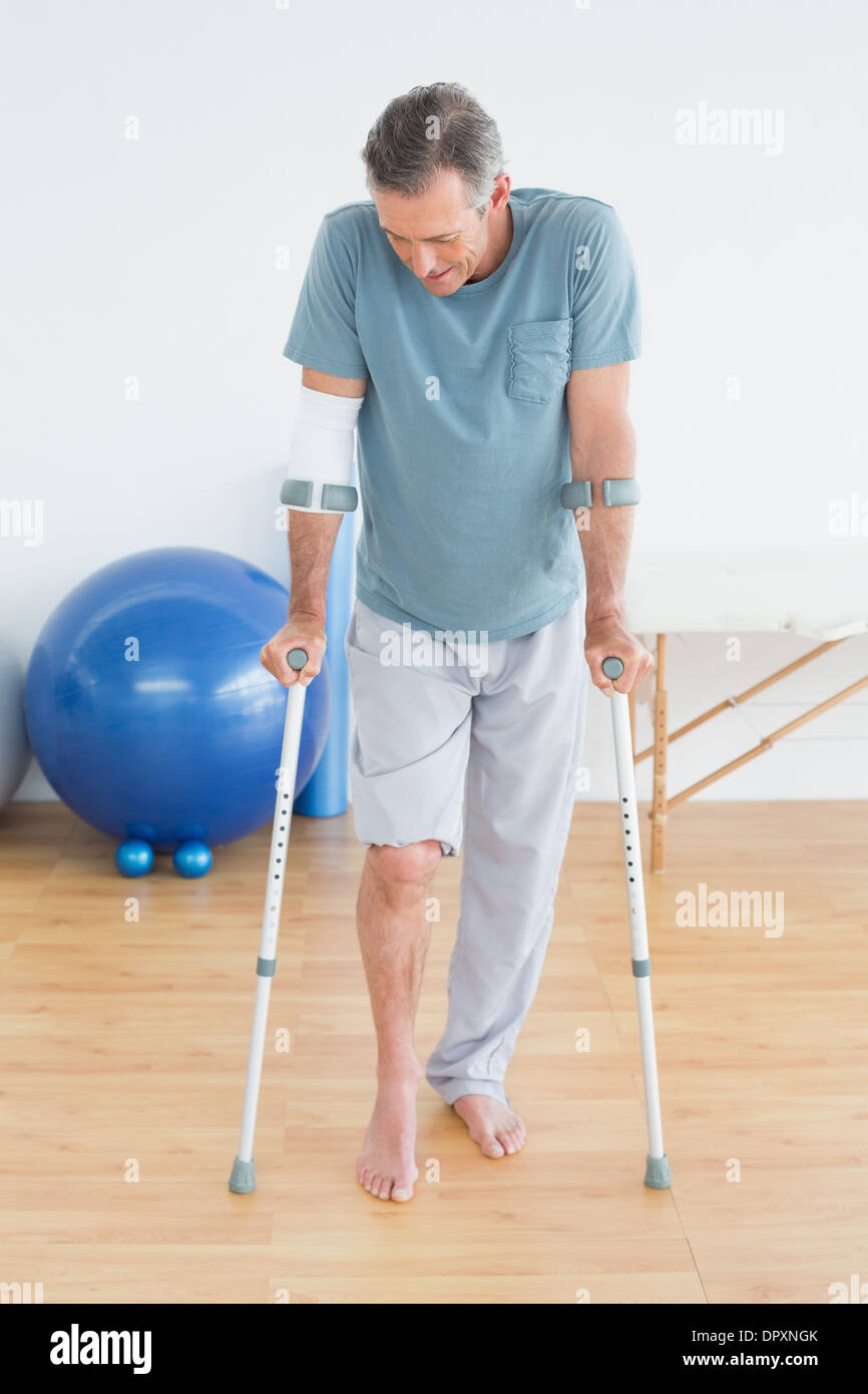 Mature man with crutches at gym hospital Stock Photo
