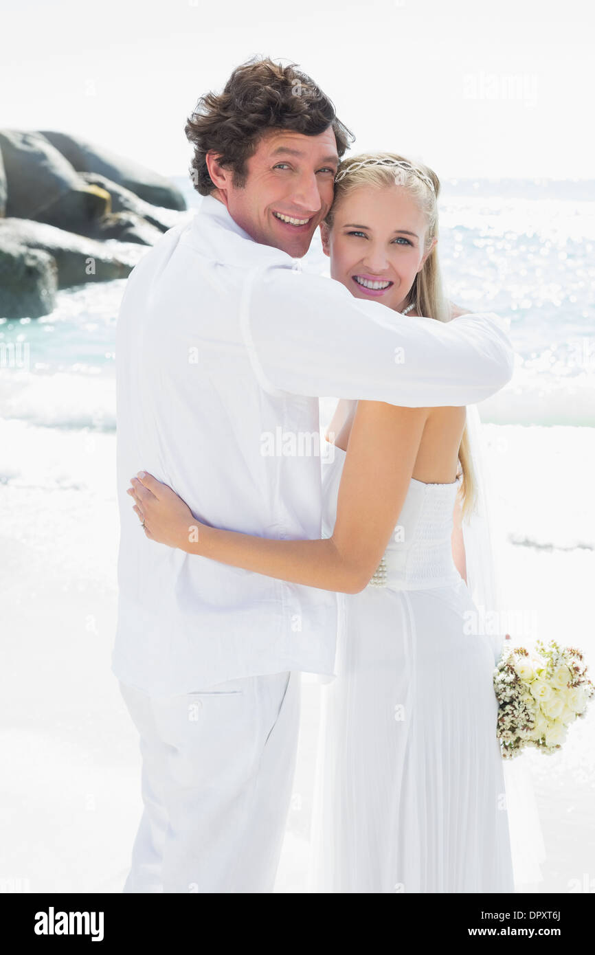 Smiling bride and groom looking at camera hugging Stock Photo