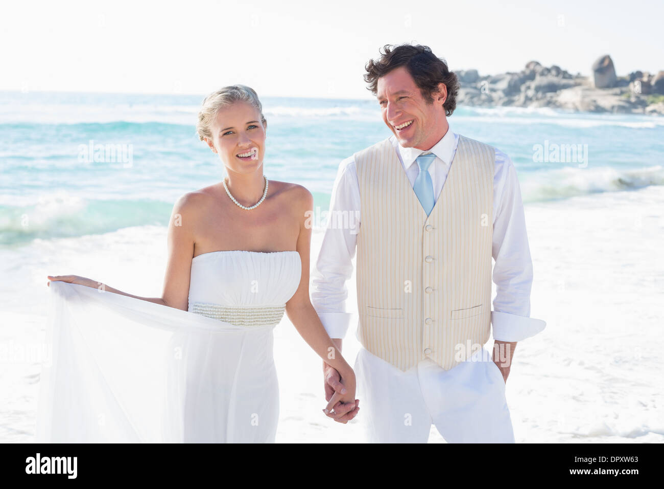 Newlyweds walking hand in hand and smiling Stock Photo