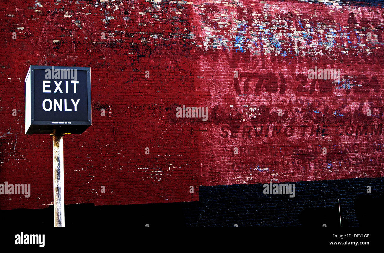 Feb 12, 2009 - Chicago, Illinois, USA - A wall beside a parking lot in Chicago, Illinios in the Logan Square neighborhood. The exposed red aged brick has been painted over a few times over the years, giving it a raw, deep, feeling with character. In front is an exit only sign on a white street post, limiting escape. (Credit Image: © Steven Karl Metzer/ZUMA Press) Stock Photo