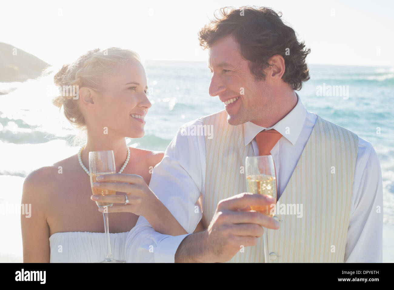 Young newlyweds having champagne linking arms Stock Photo