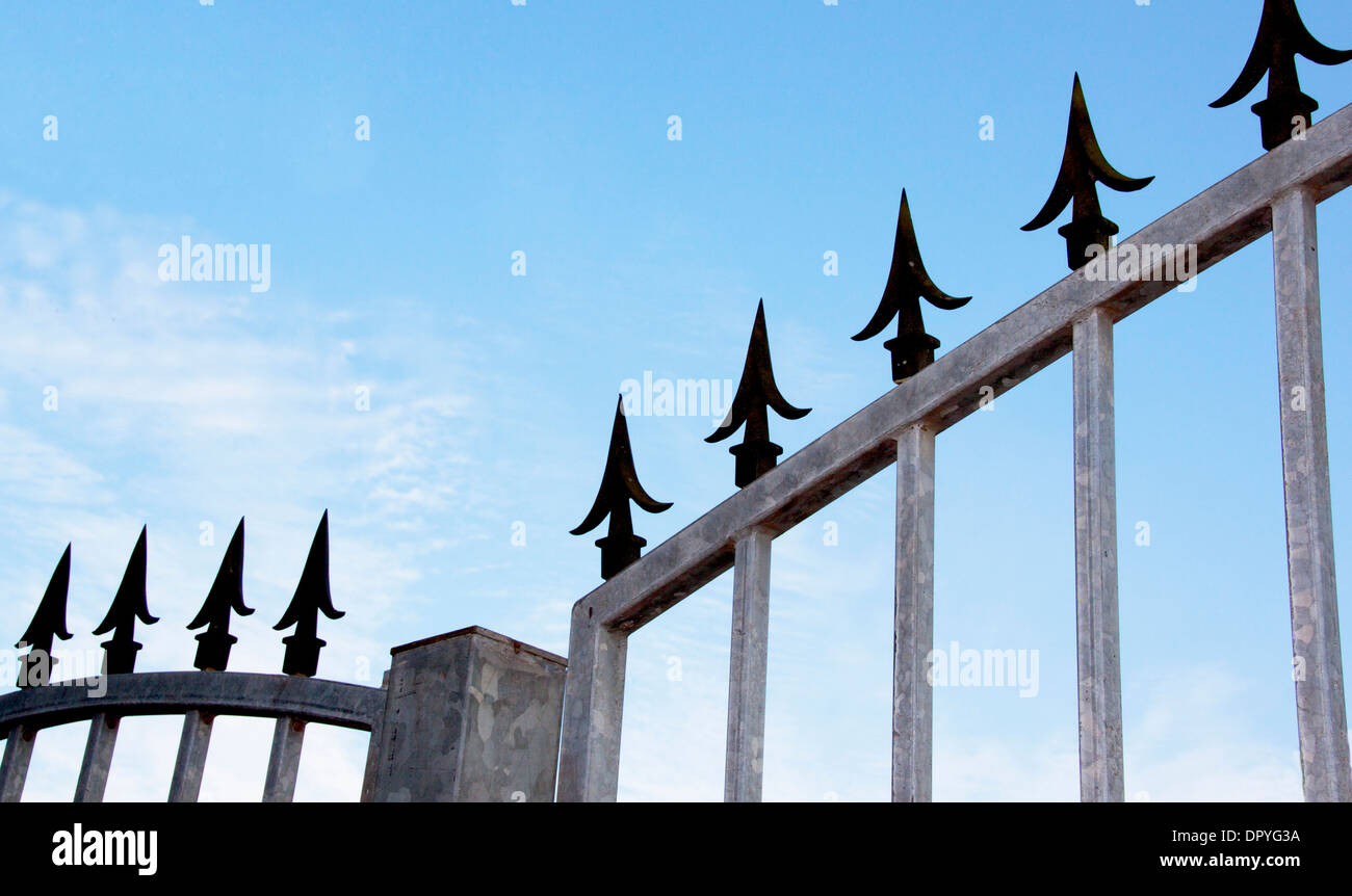 Closeup of decorative black spikes on top of galvanized security gate