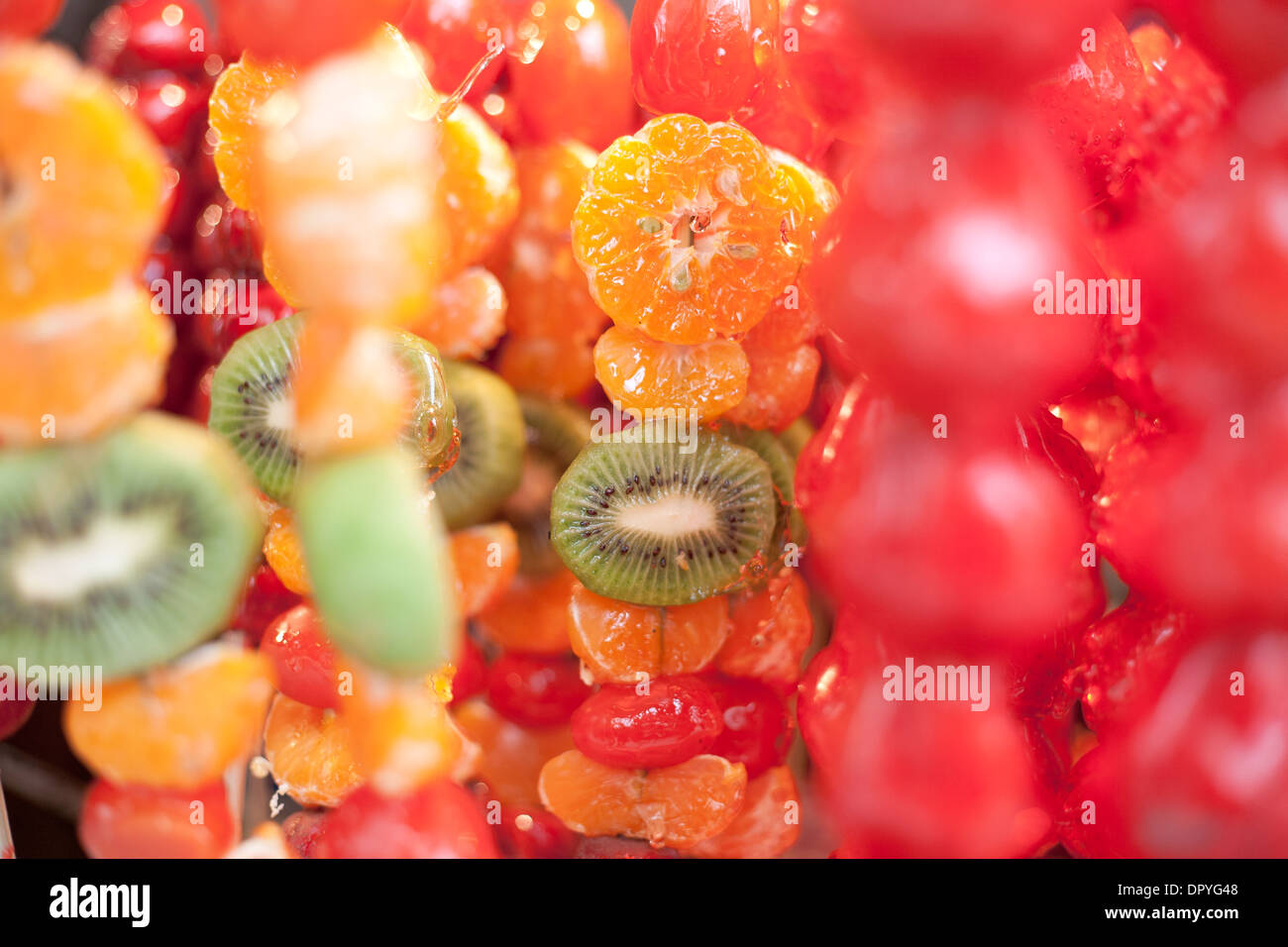 Kiwi, tangerine, apple glazed fruit on a stick. Chinese street food