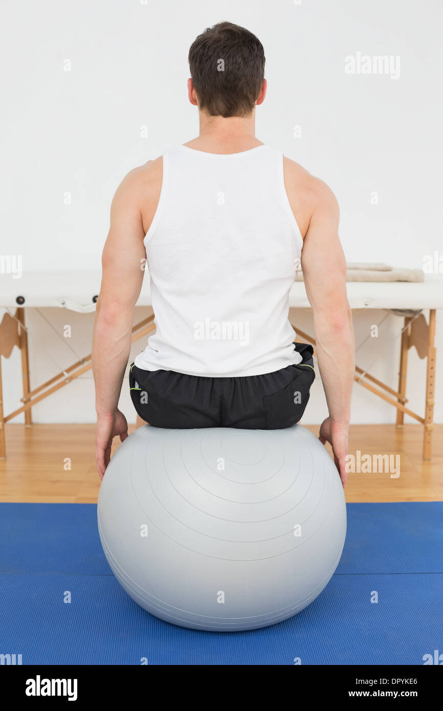Rear view of a young man sitting on yoga ball Stock Photo