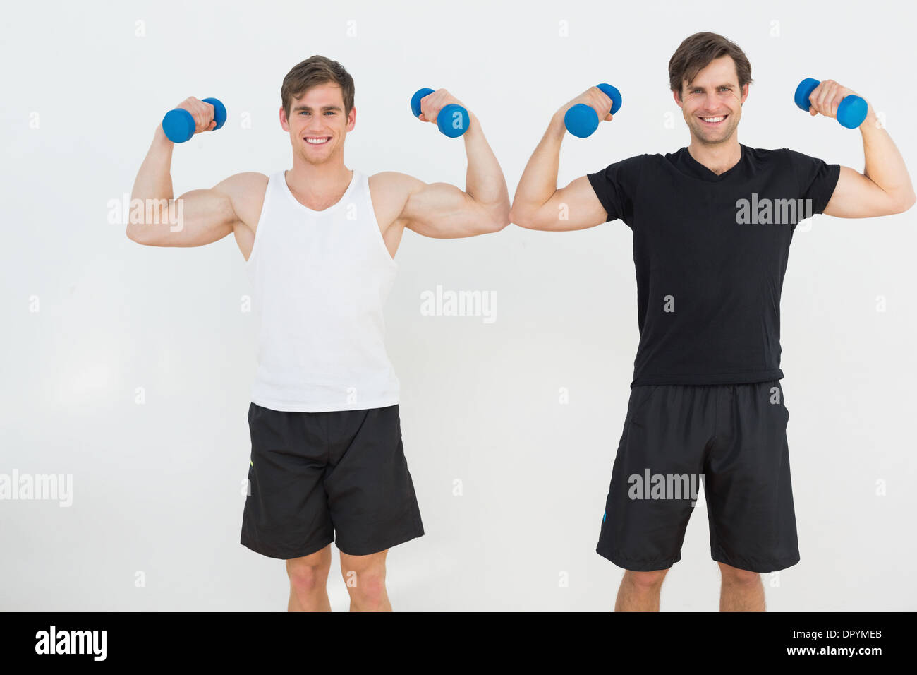 Portrait of two young men flexing muscles with dumbbells Stock Photo