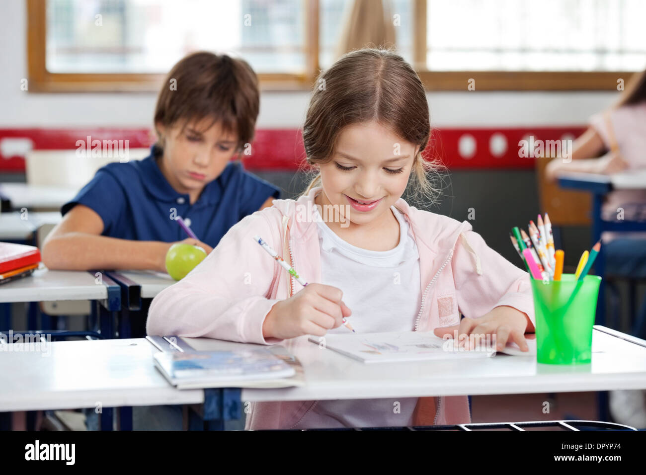 Schoolgirl Smiling While Drawing In Classroom Stock Photo - Alamy