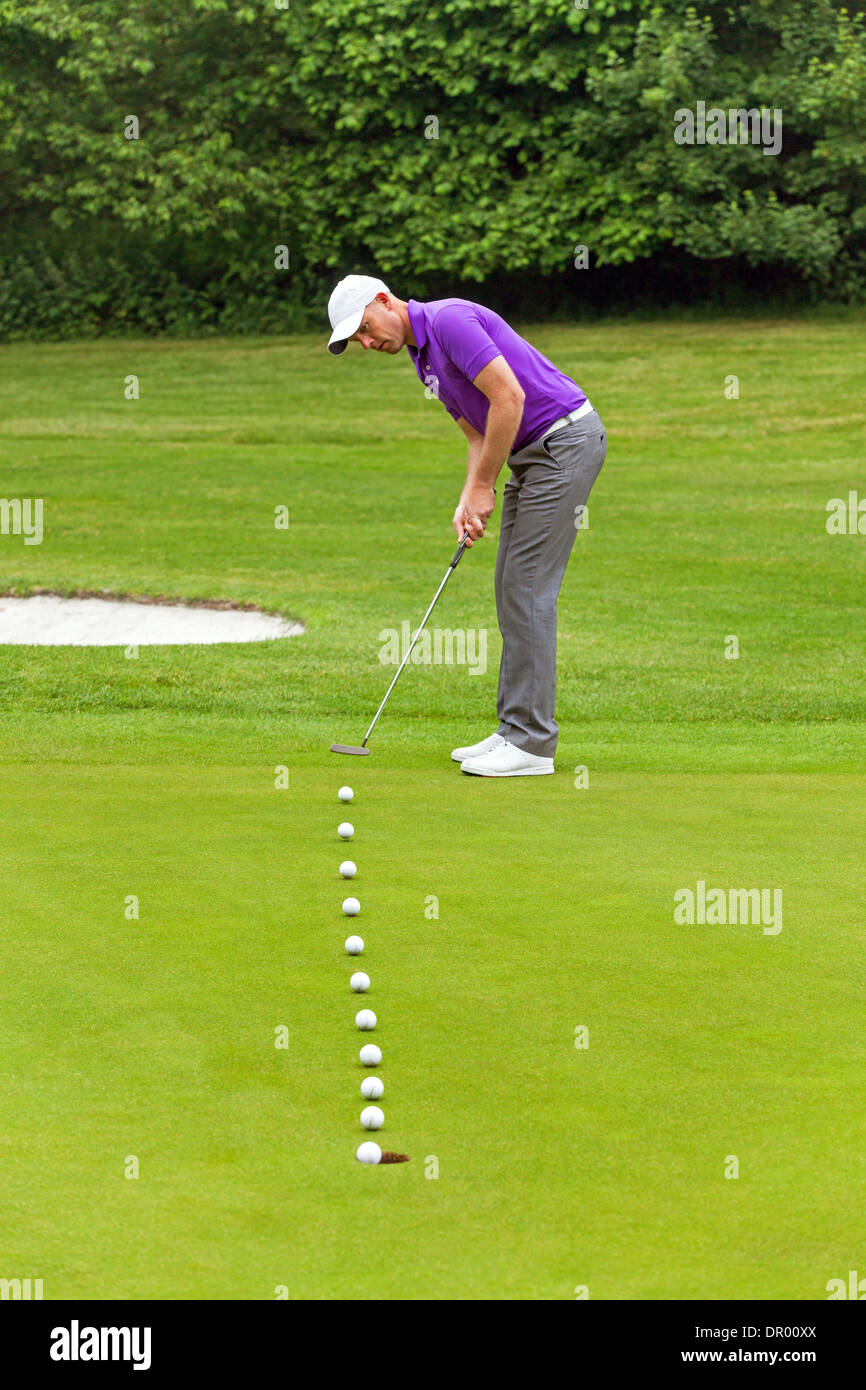 Multiple frame photo of a golfer putting with the line of the ball shown as it travels into the hole. Stock Photo