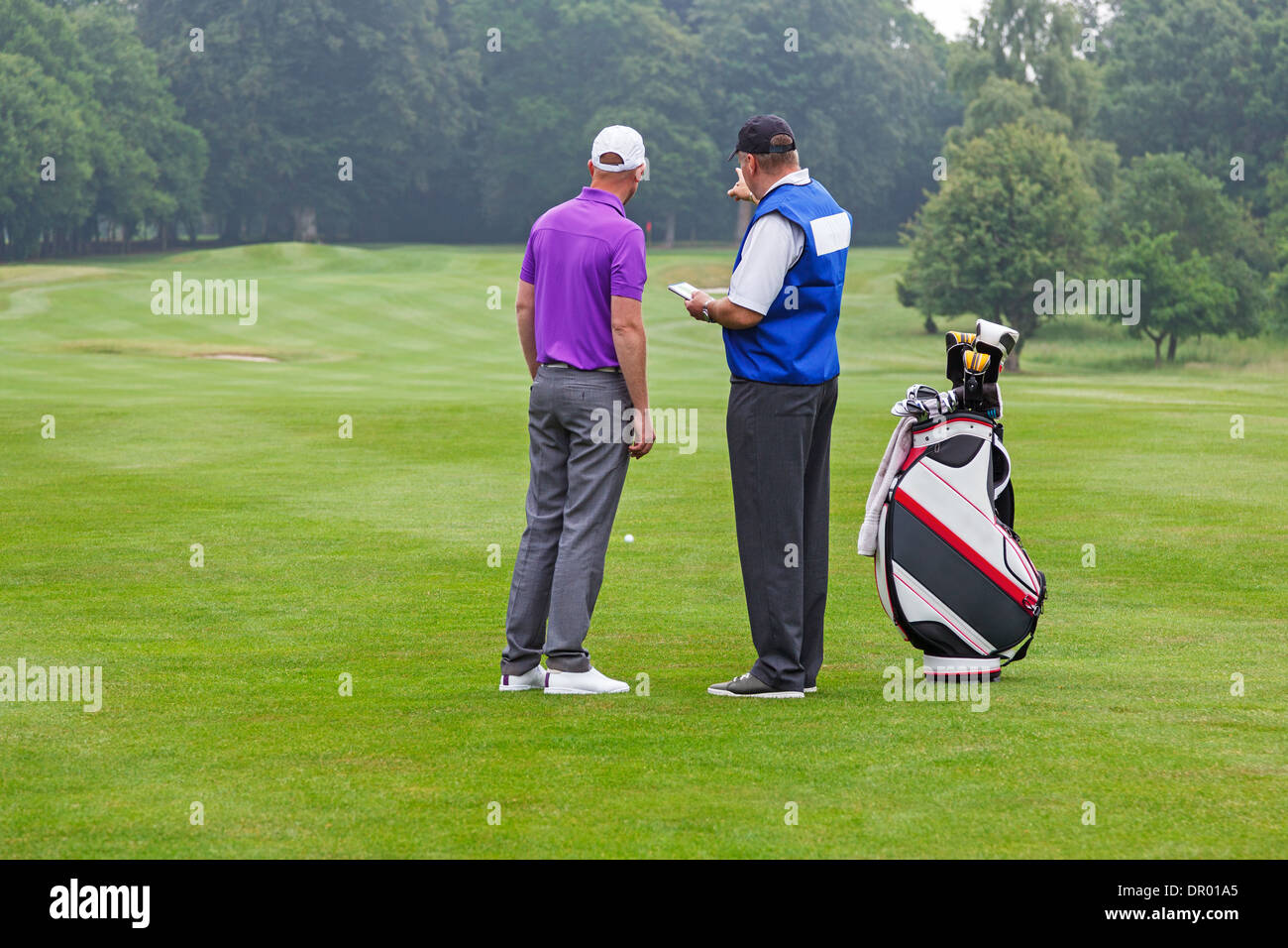 Caddy pointing out a hazard to the golfer on a par 4 fairway Stock Photo
