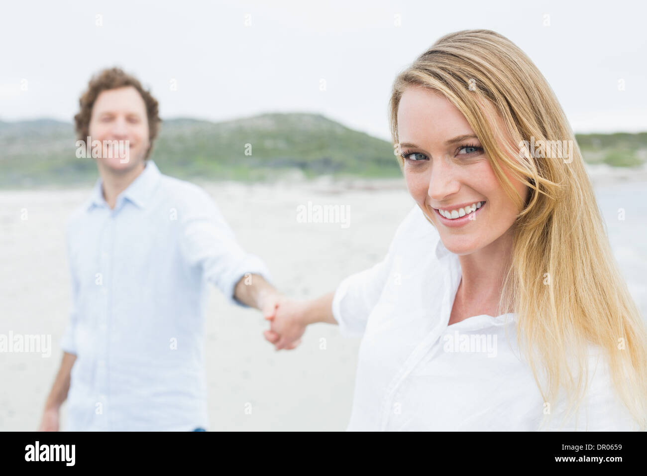 Smiling casual couple holding hands at beach Stock Photo