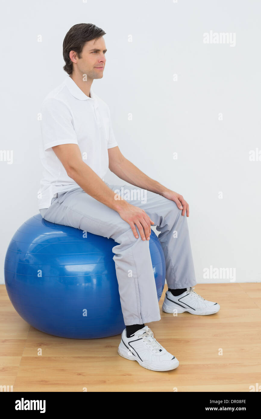 Young man sitting on exercise ball in hospital gym Stock Photo