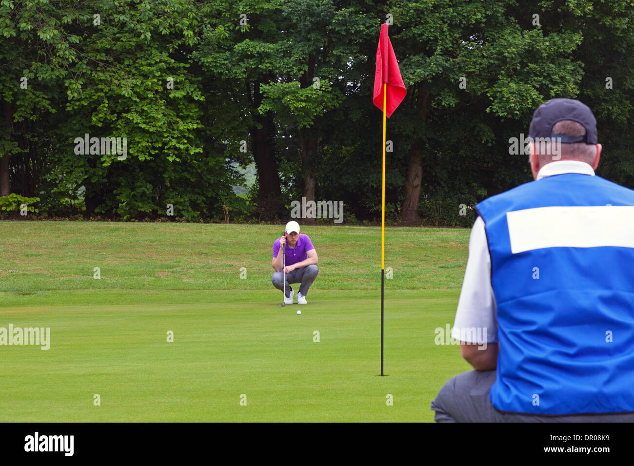 A professional golfer and his caddy reading the green to judge the line of the putt. Series of three photos. Stock Photo
