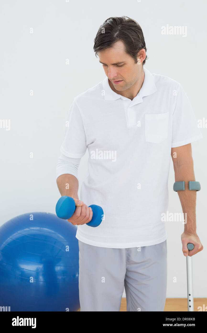 Young man with crutch and dumbbell Stock Photo