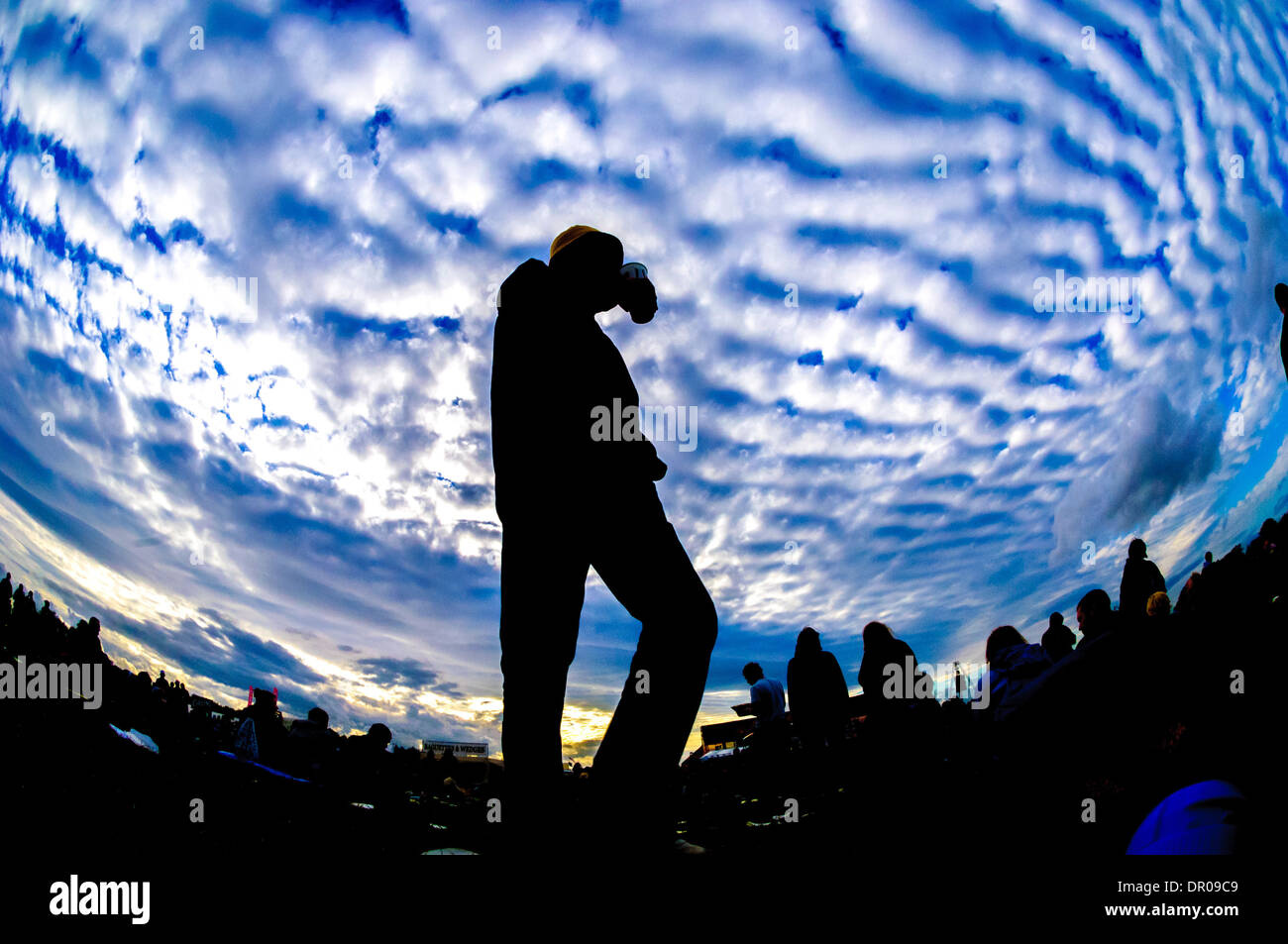 Festival goers silhouetted against cloudy blue sky Stock Photo