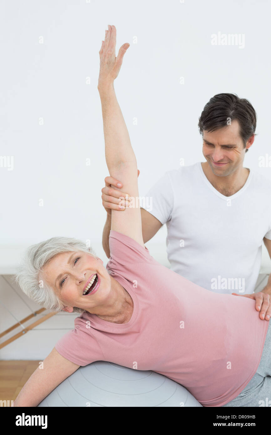 Physical therapist assisting senior woman with yoga ball Stock Photo