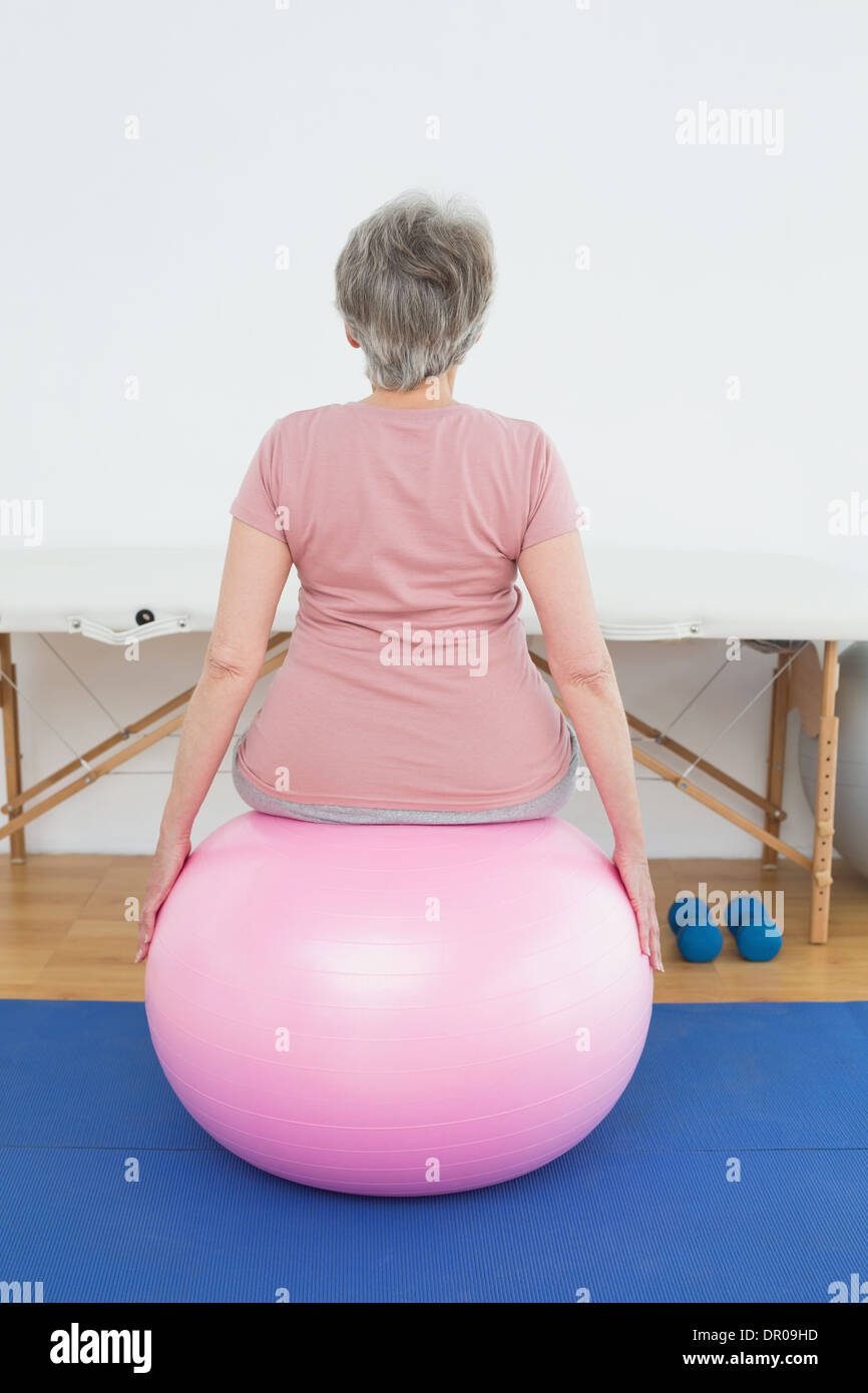 Rear view of a senior woman sitting on yoga ball Stock Photo