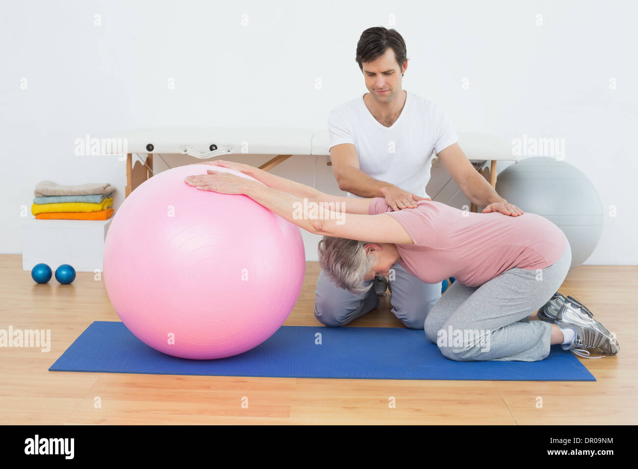 Physical therapist assisting senior woman with yoga ball Stock Photo