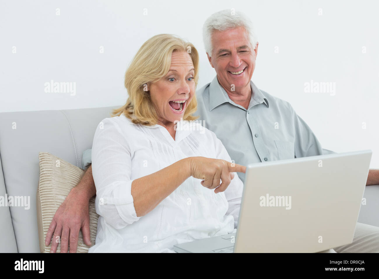 Cheerful senior couple using laptop at house Stock Photo