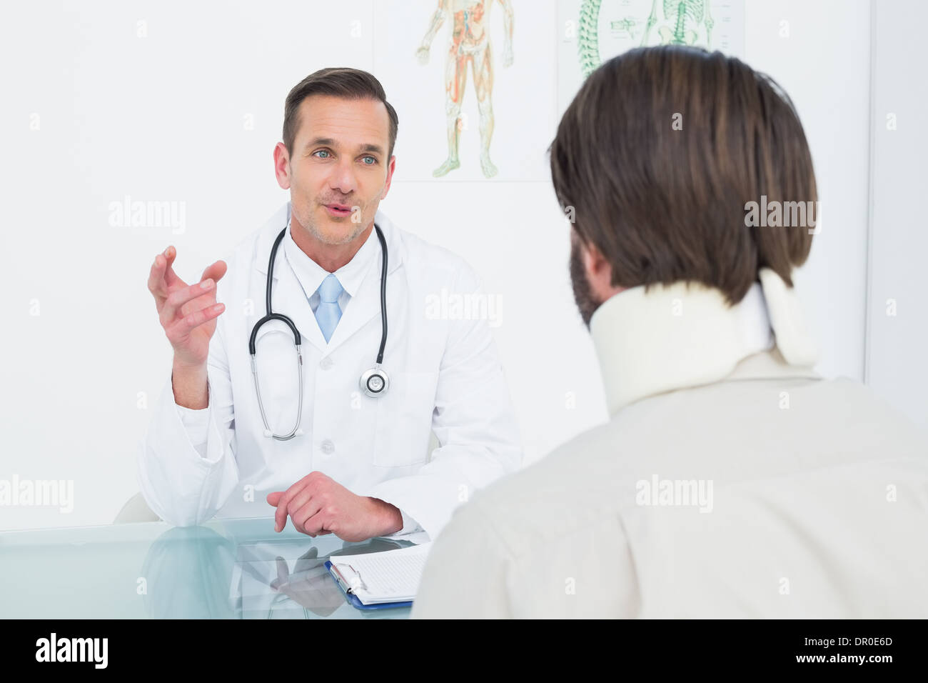 Male doctor in communication with patient at desk Stock Photo