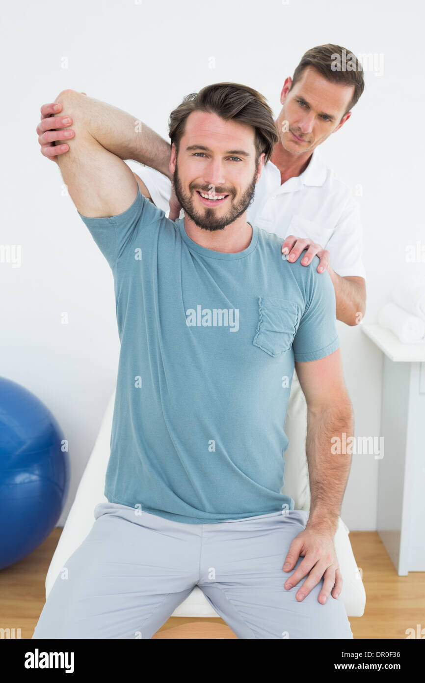 Male physiotherapist stretching a smiling man's arm Stock Photo