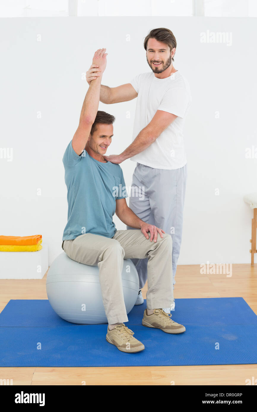 Man on yoga ball working with a physical therapist Stock Photo