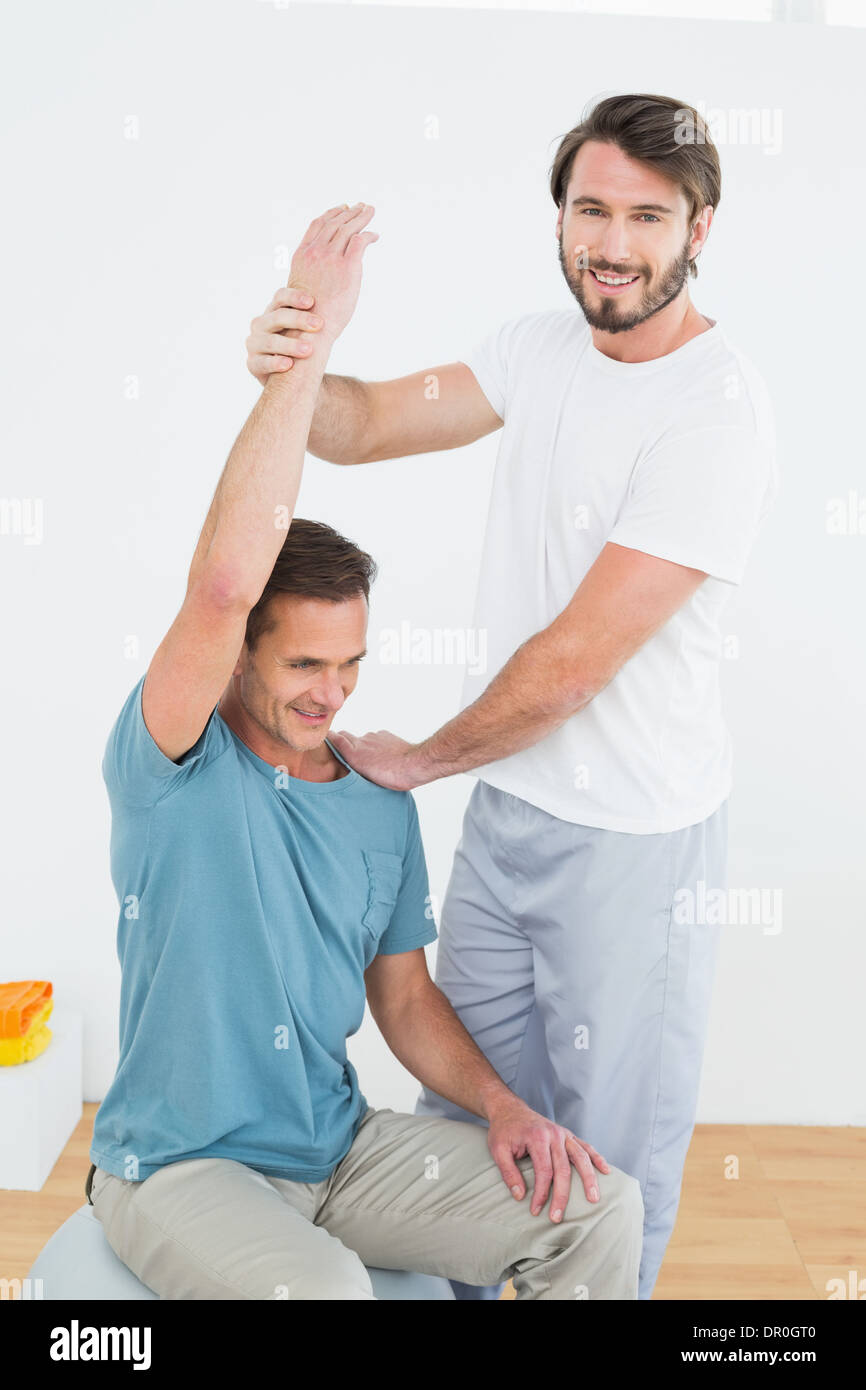 Physical therapist assisting man with stretching exercises Stock Photo