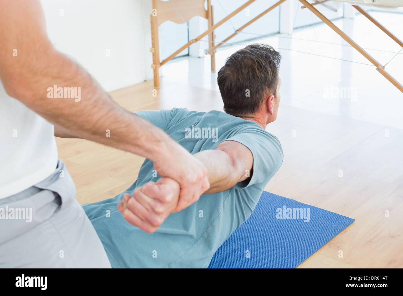 Therapist assisting man with stretching exercises Stock Photo Alamy