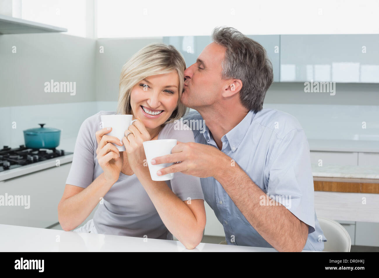 Loving couple with coffee cups in kitchen Stock Photo