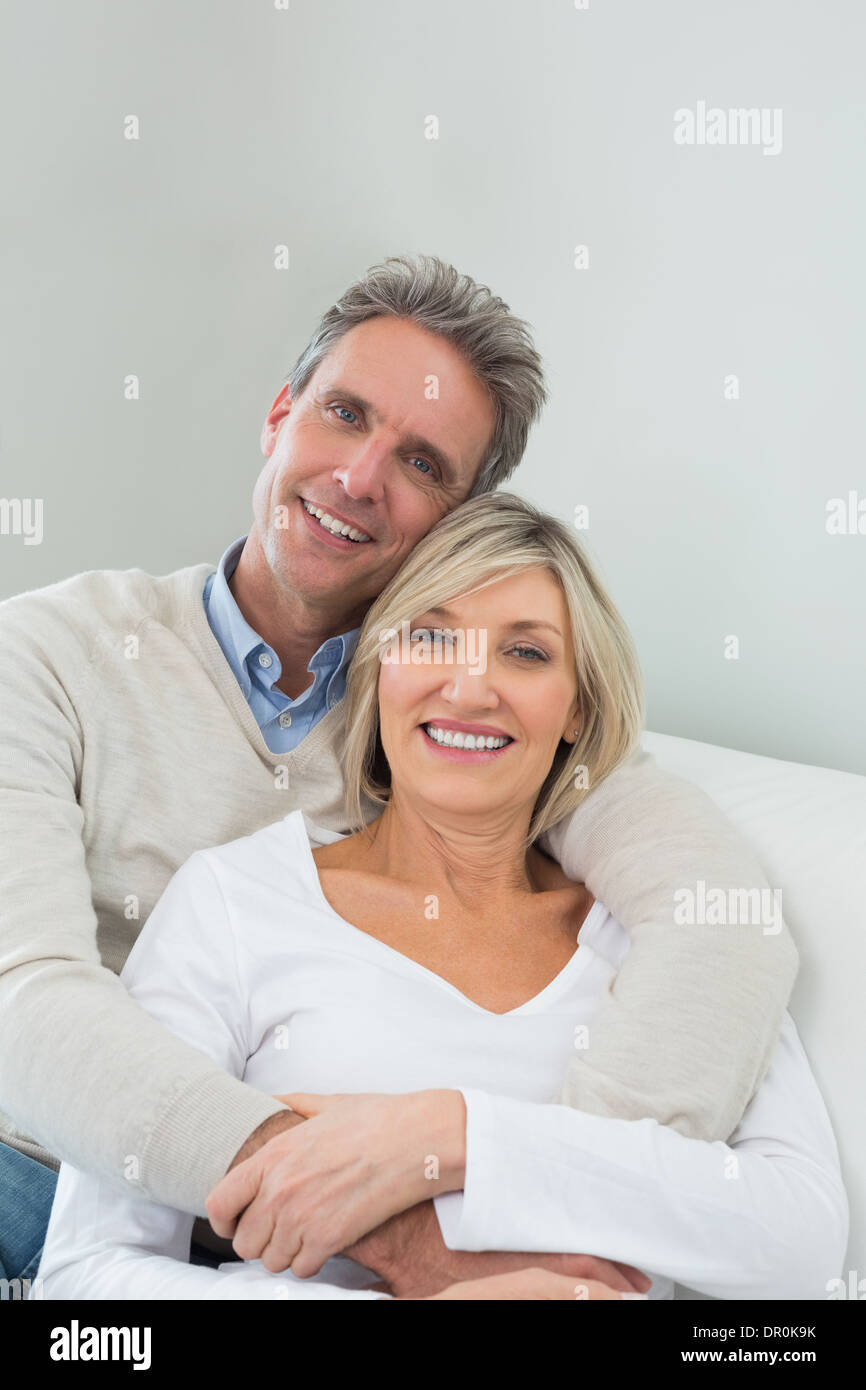 Happy couple embracing while sitting on sofa at home Stock Photo