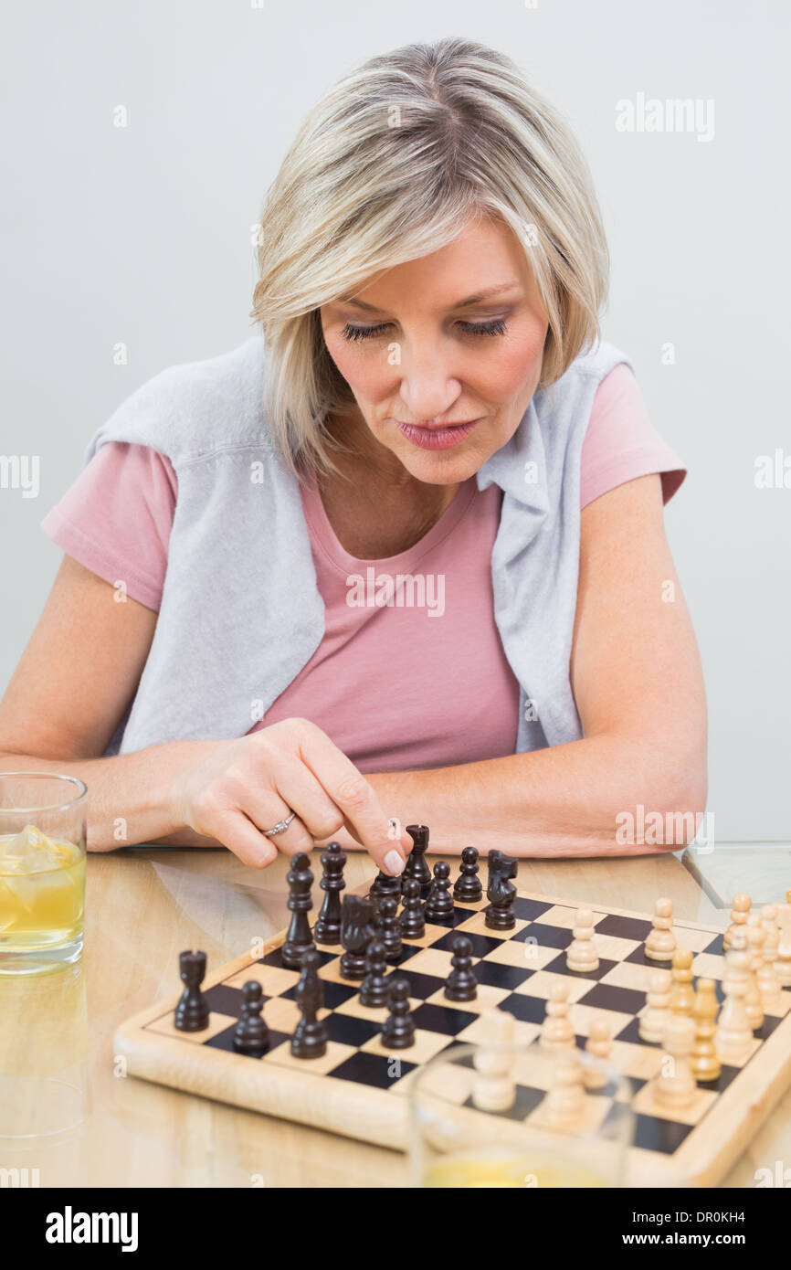 Concentrated woman playing chess at table Stock Photo