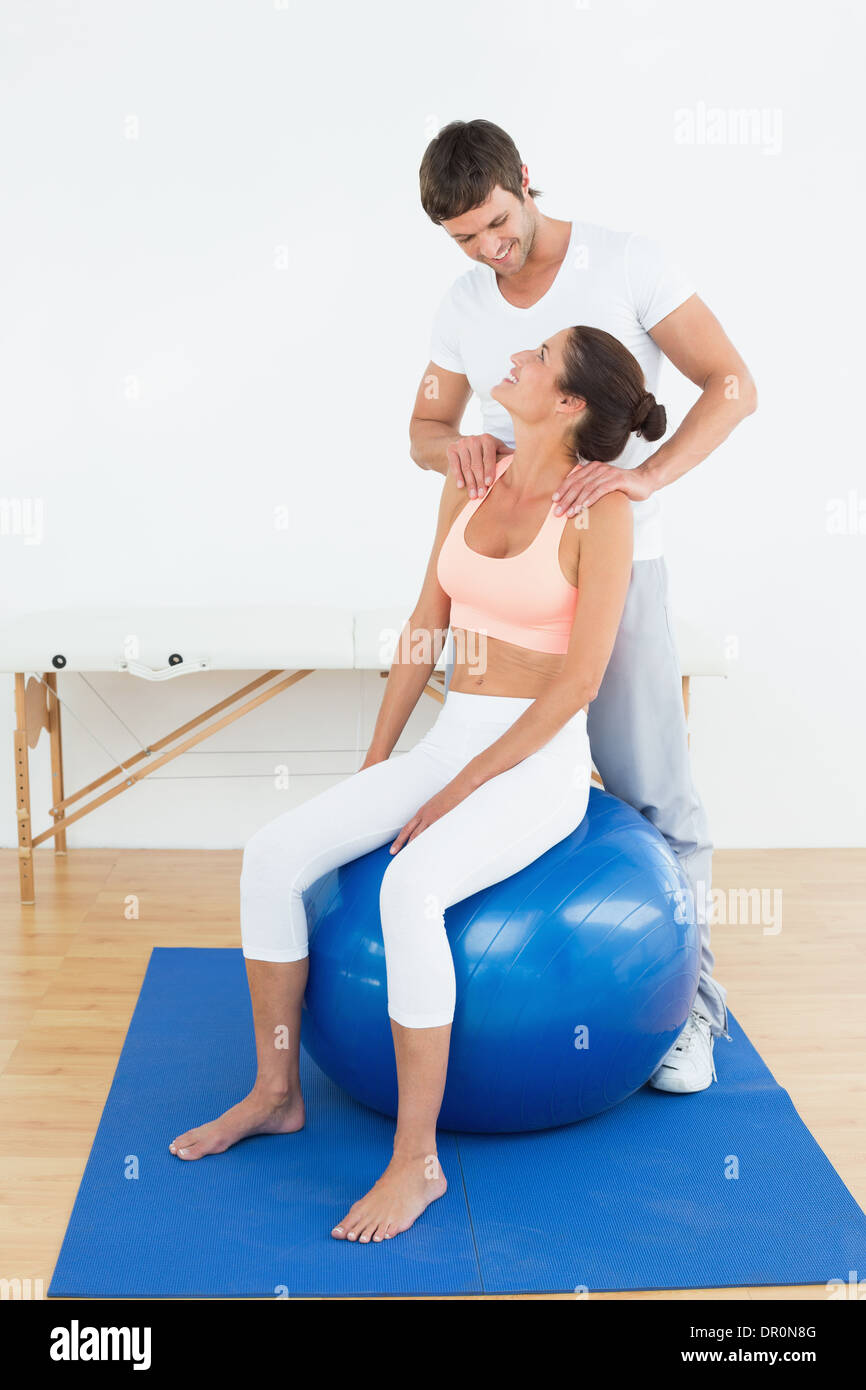 Woman on yoga ball working with physical therapist Stock Photo