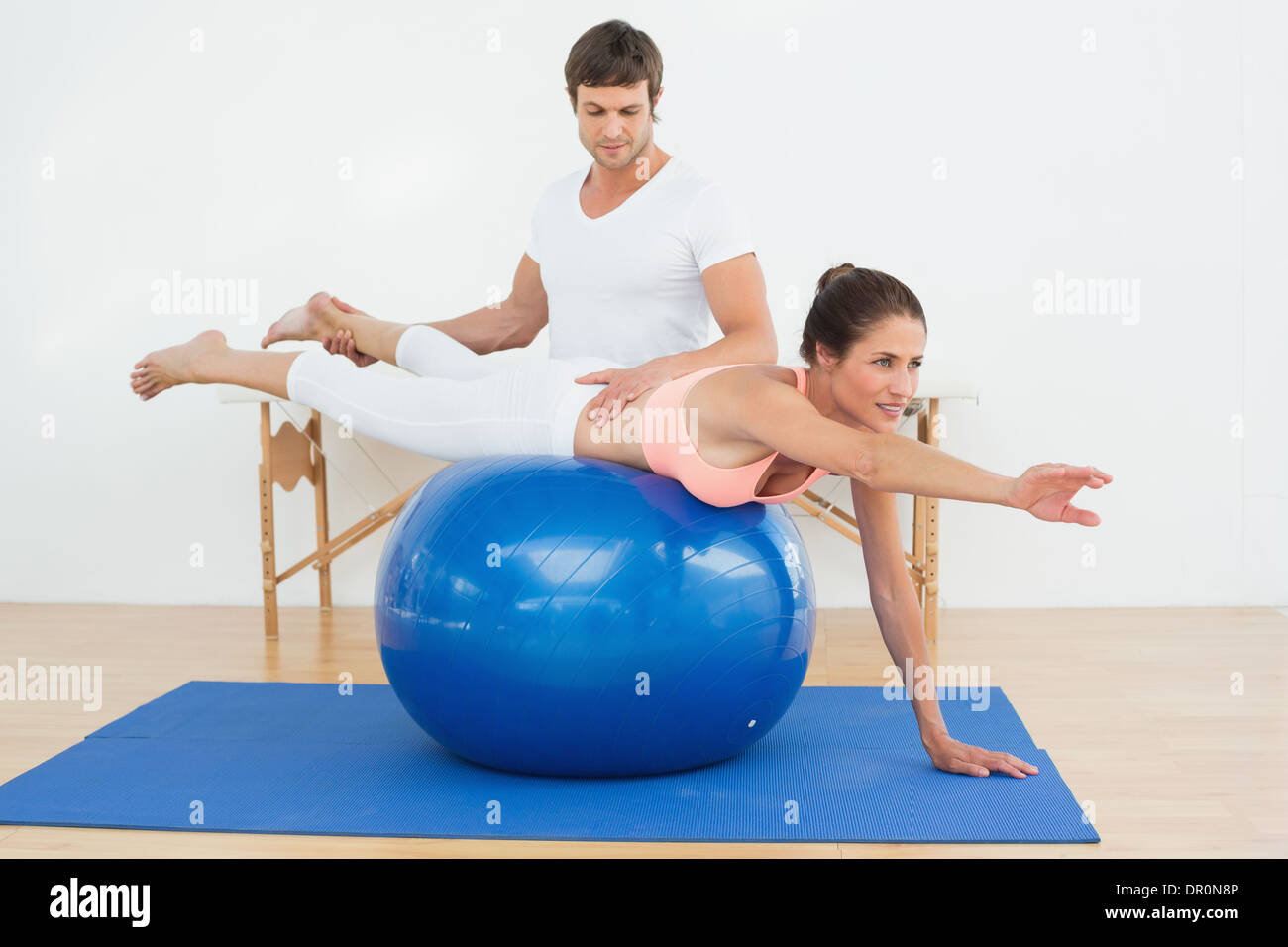 Physical therapist assisting young woman with yoga ball Stock Photo