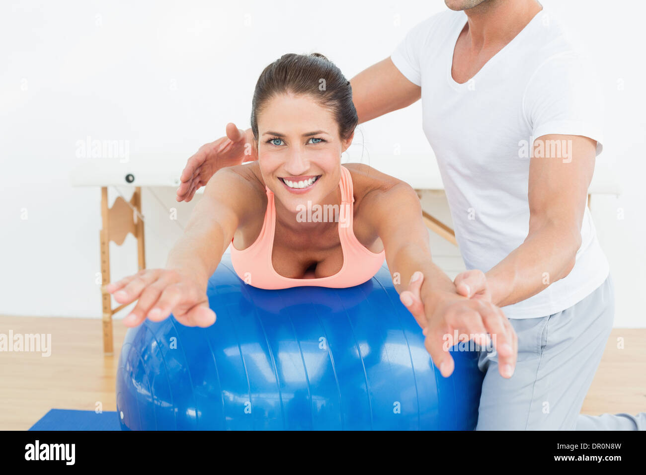Physical therapist assisting woman with yoga ball Stock Photo