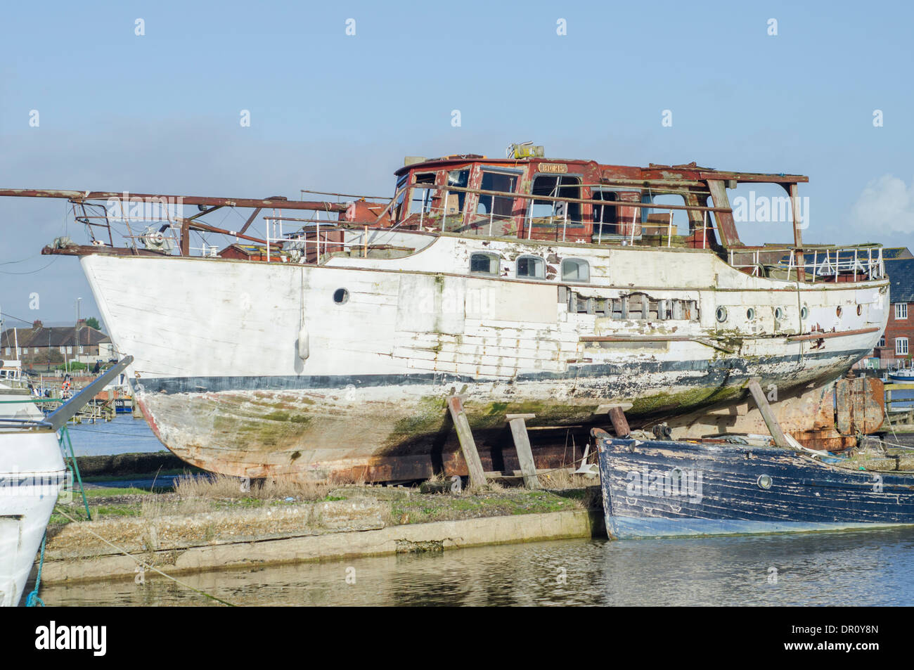 A wooden decaying boat out of the water by a river. Stock Photo