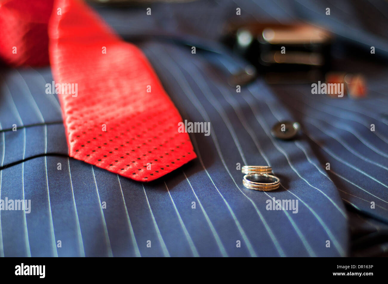 wedding rings, red tie, belt and cuff links lie on a wedding suit of