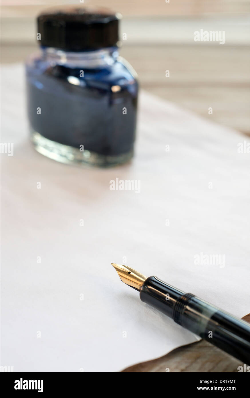 fountain pen, ink, and sheet of paper on a wooden table Stock Photo