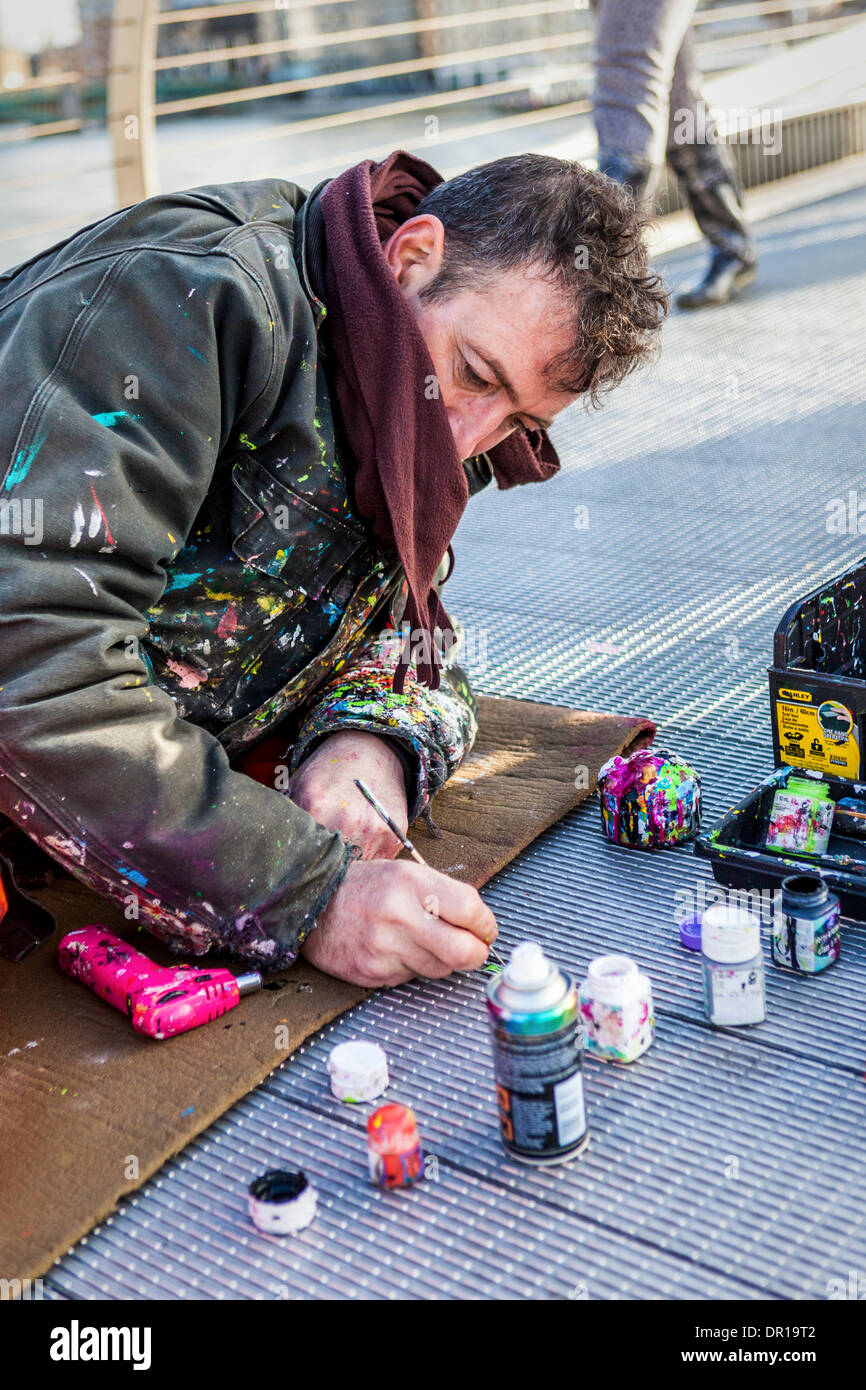 London, UK, 16th January 2014 . Artist, Ben Wilson, creates art on the Millenium Bridge The English artist is painting discarded chewing gum blotches on the bridge and the miniature art works are drawing crowds of admiring viewers. Credit:  Eden Breitz/Alamy Live News Stock Photo