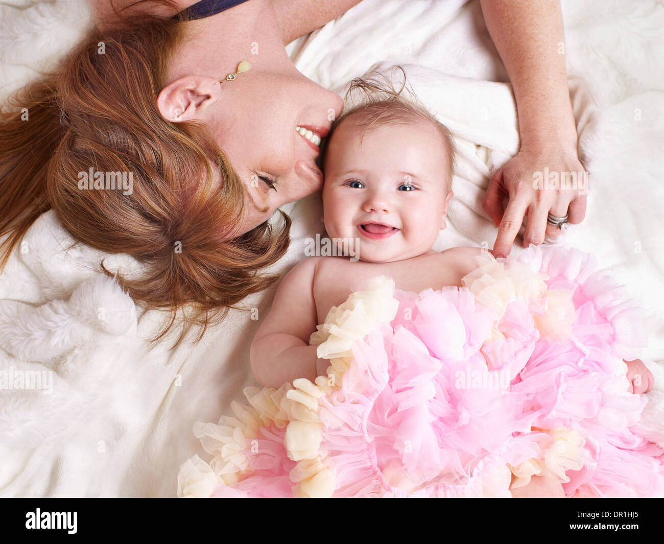 Mother and baby girl laying on bed Stock Photo