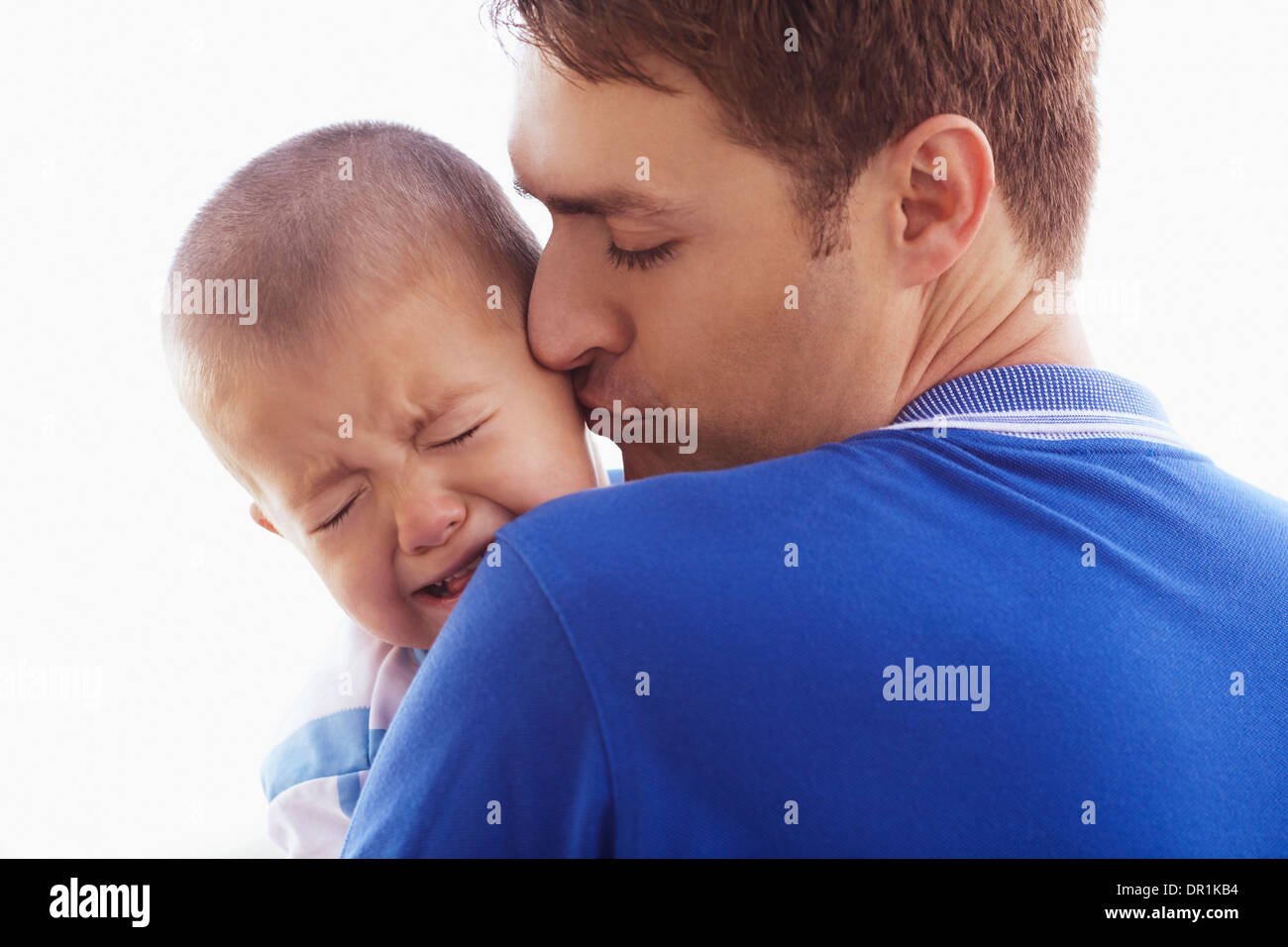 Father kissing crying son Stock Photo