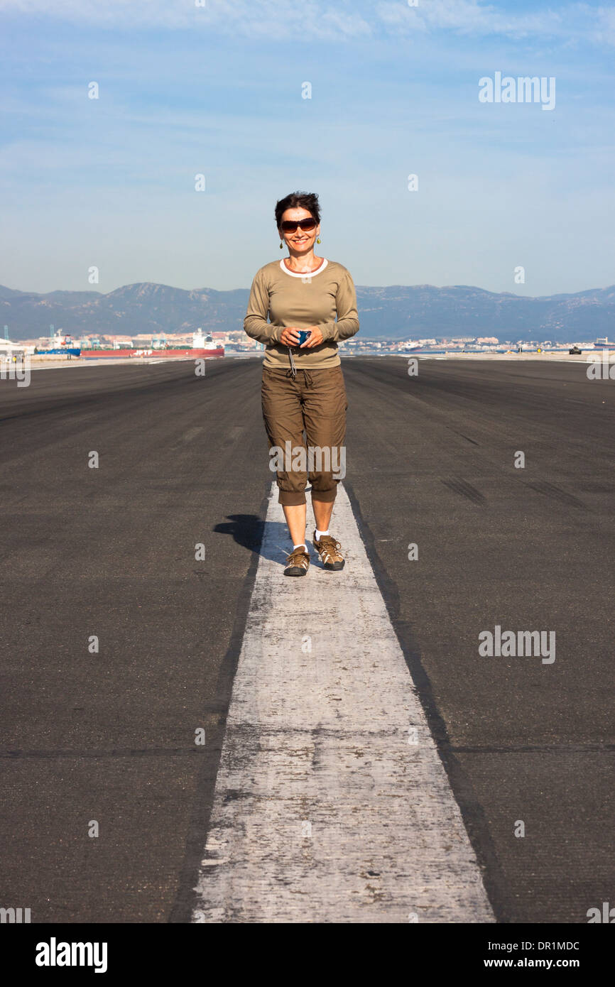 Portrait of happy smiling woman tourist standing at the airport runway. Stock Photo