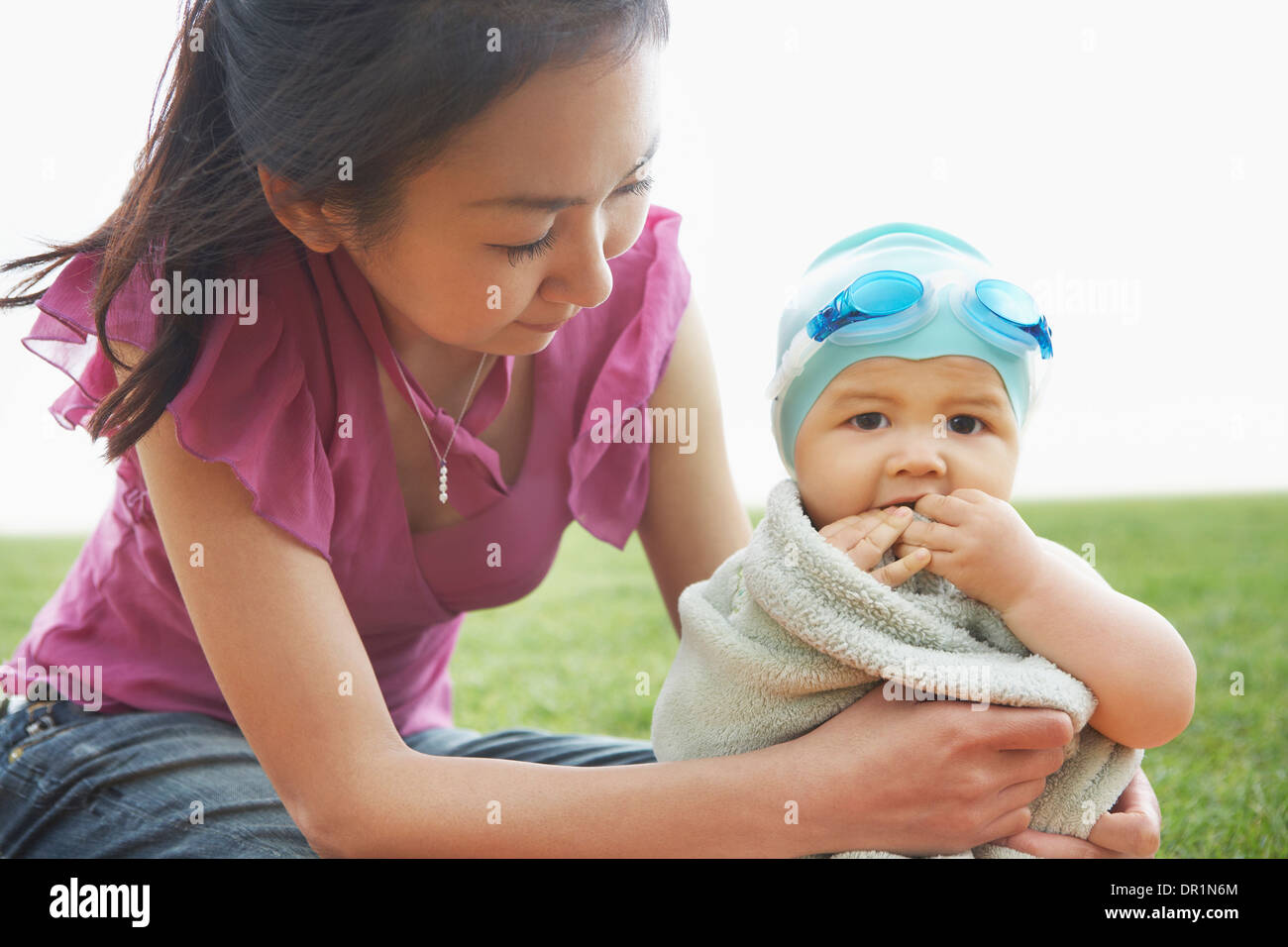 Mother wrapping baby in towel outdoors Stock Photo