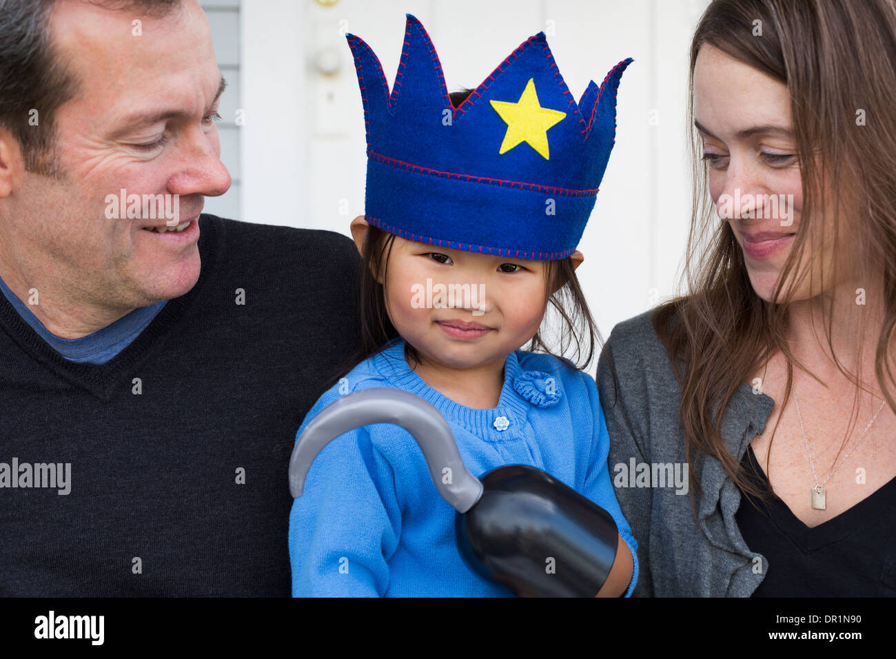 Parents holding daughter with hook and crown Stock Photo