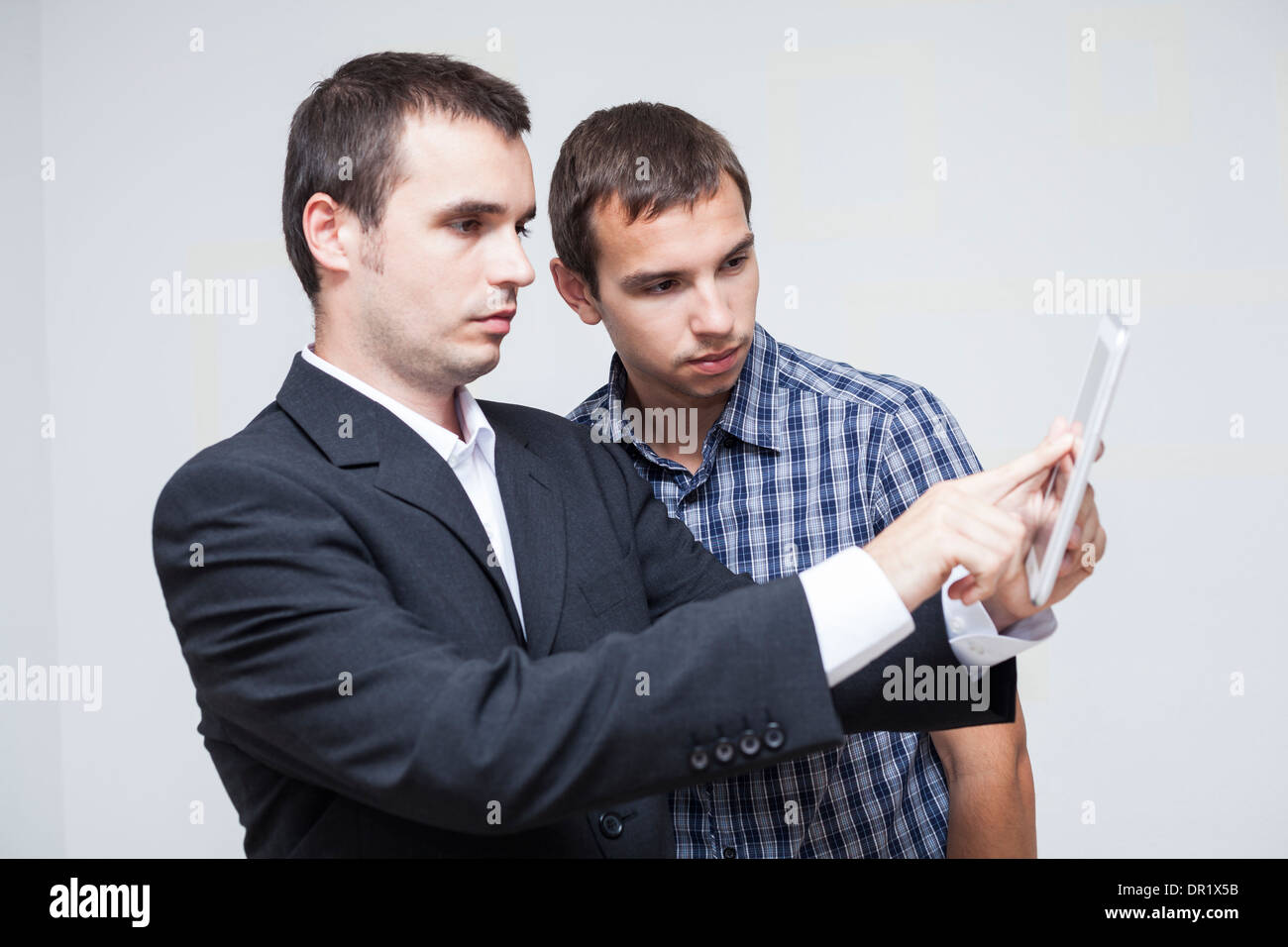 Two serious businessmen looking at digital tablet. Stock Photo