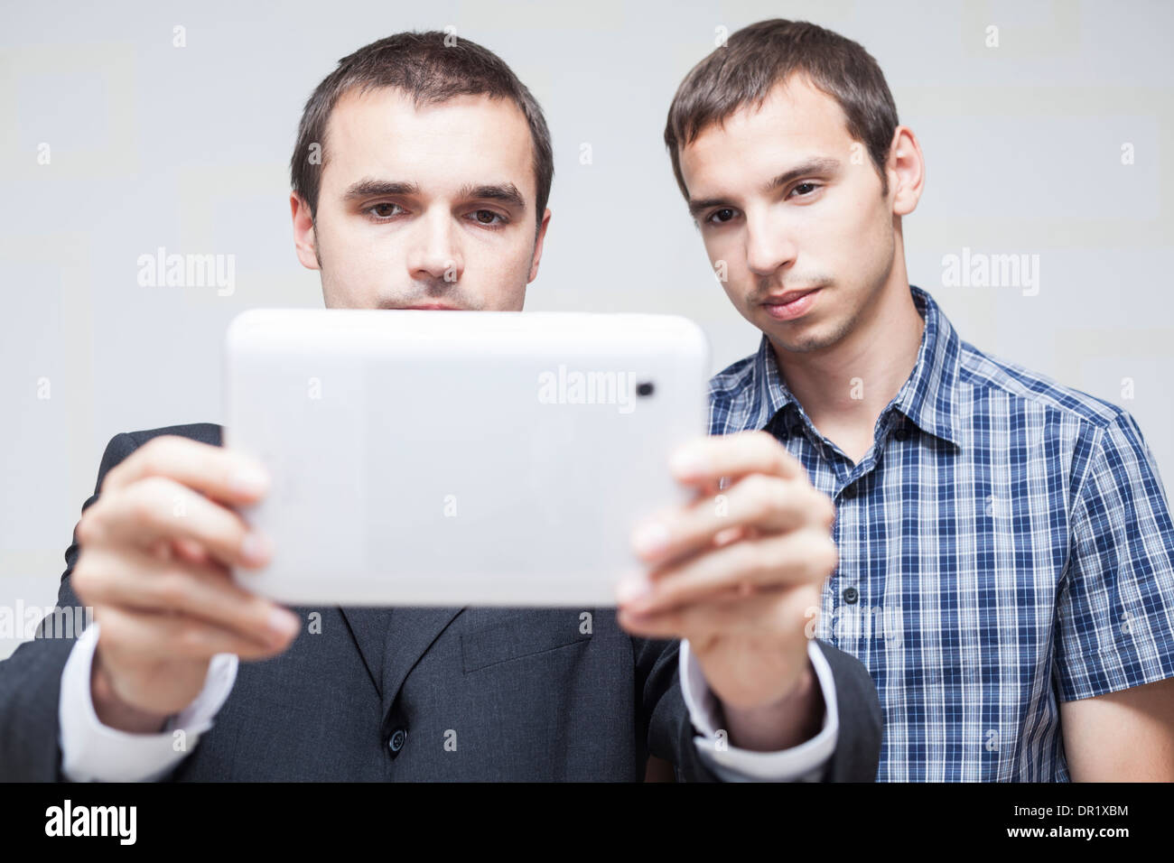 Two serious businessmen looking at digital tablet. Stock Photo