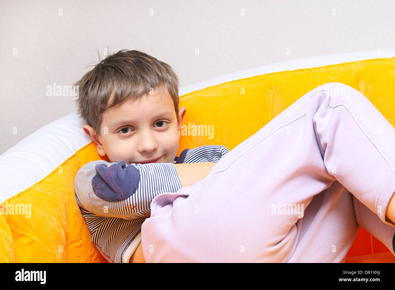 The boy of 6-7 years idly laying in an armchair Stock Photo