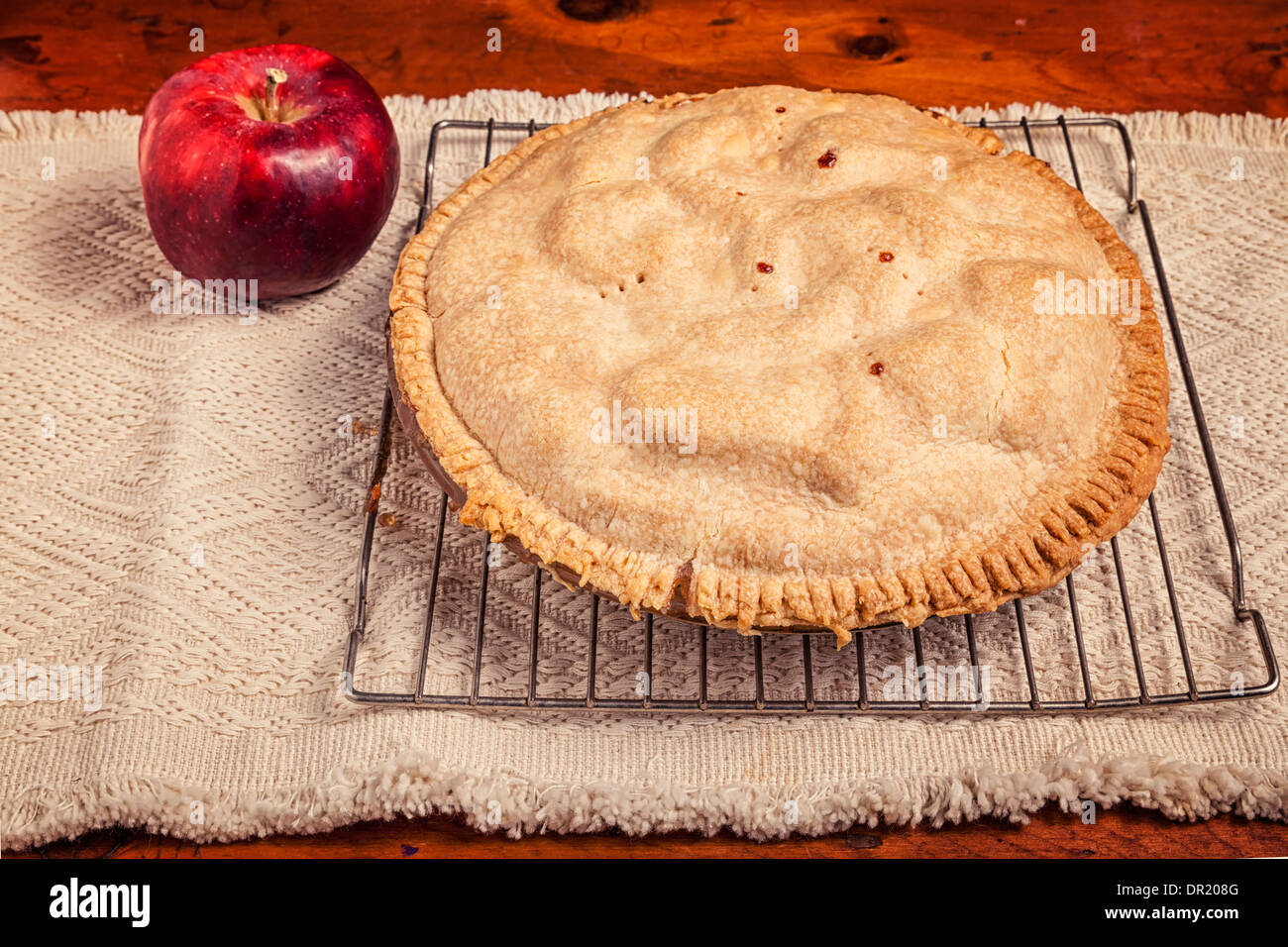 Homemade apple pie cooling on a wire baking rack and sitting beside a cortland apple. Stock Photo