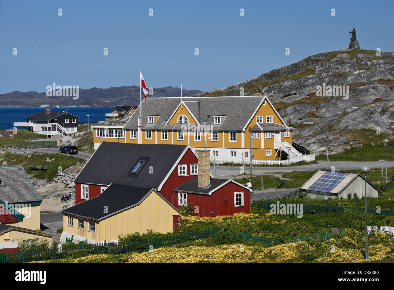 Hans Egede statue on hill, Hans Egede house (yellow in background), and colorful houses in Nuuk (Godthab), Greenland Stock Photo