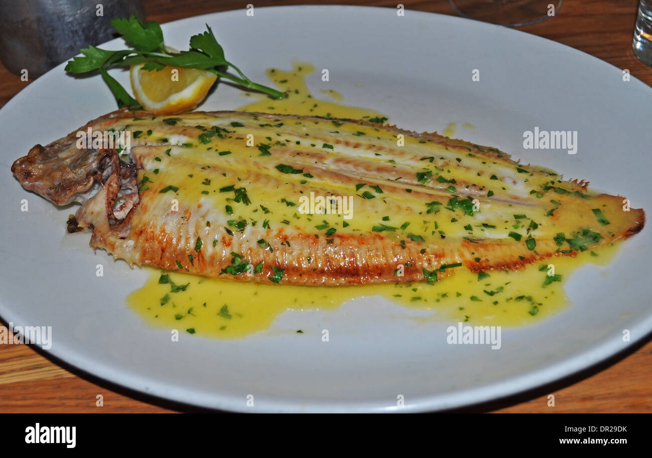 Dover sole with lemon and parsley butter sauce served on a white china