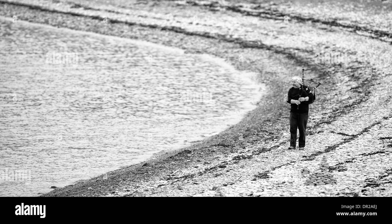 Man Playing the Bagpipes on Ardmair Beach, Scotland. Stock Photo